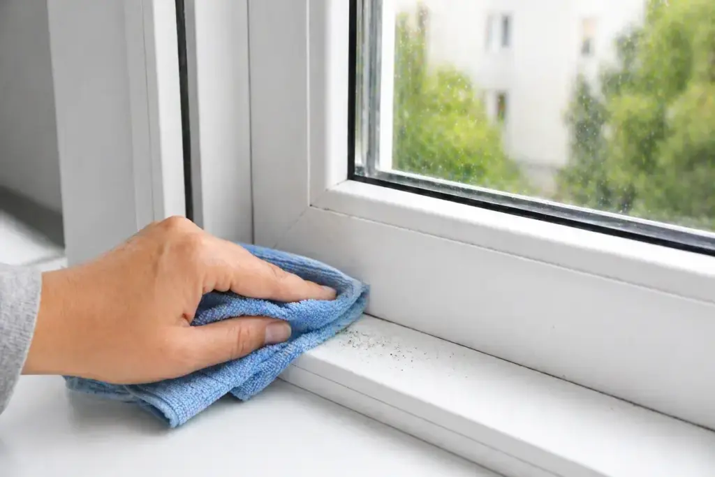 Weißer Kunststofffensterrahmen wird mit Mikrofasertuch gereinigt und von Schmutz befreit