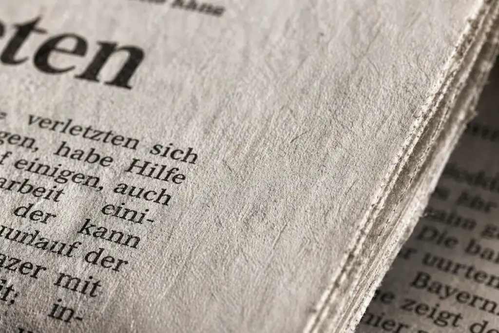 Nahaufnahme der rauen Struktur von Zeitungspapier mit sichtbaren Papierfasern und Drucktext